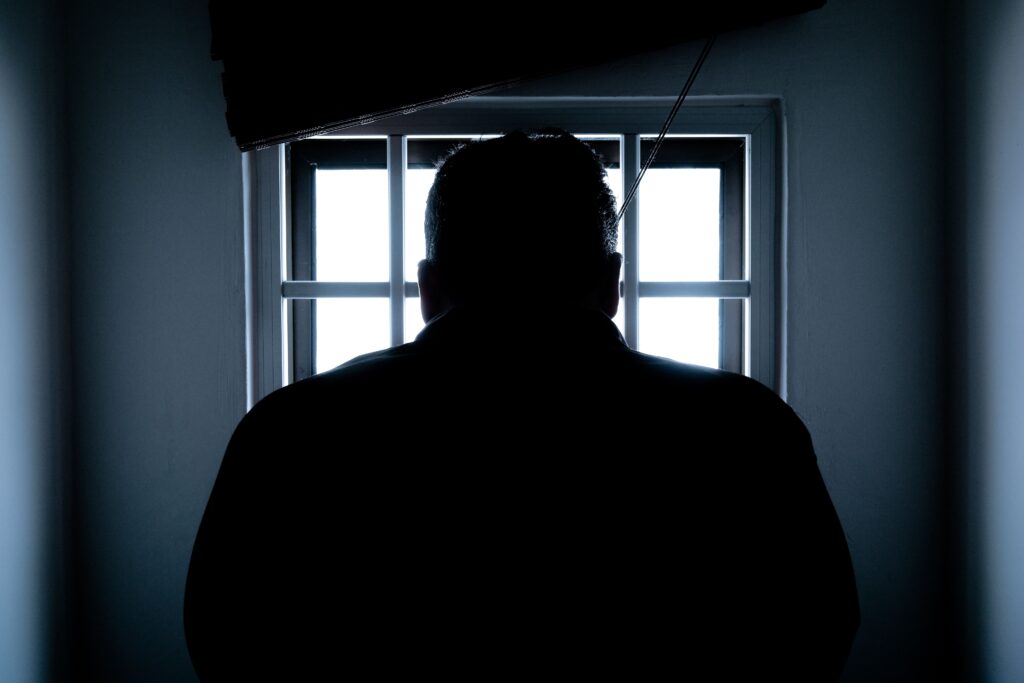 un hombre frente a una ventana en la cárcel