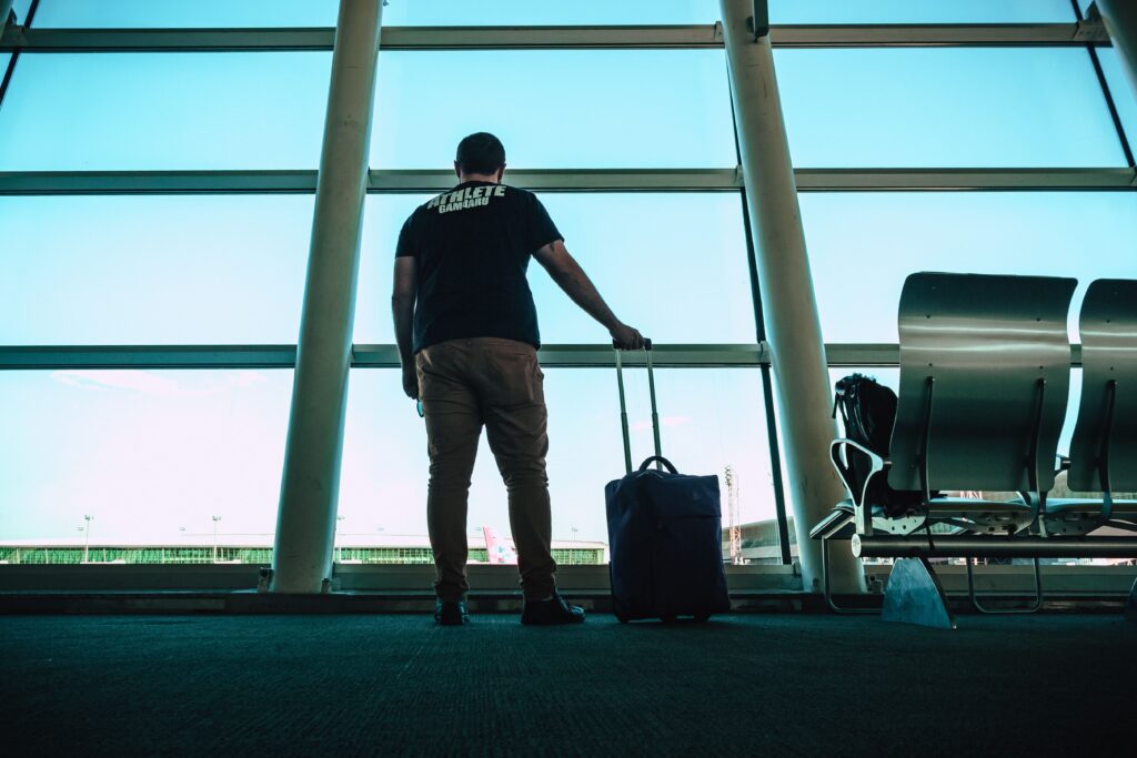 extranjero con una maleta en el aeropuerto esperando al avión